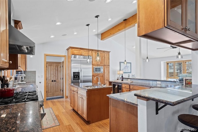 kitchen featuring beverage cooler, built in appliances, dark stone counters, lofted ceiling with beams, and wall chimney exhaust hood