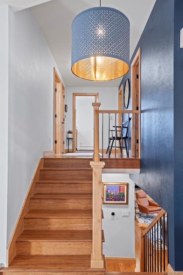 stairway featuring baseboards, baseboard heating, and wood finished floors