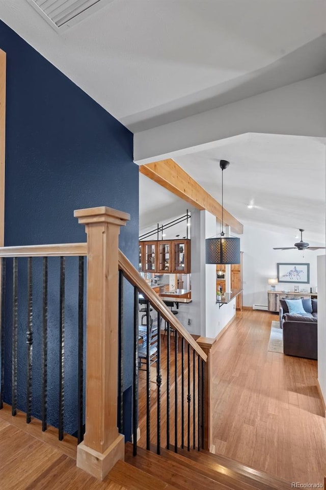 stairs featuring beam ceiling, wood finished floors, and ceiling fan