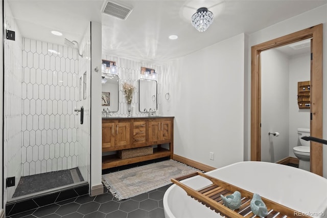 bathroom with visible vents, a shower stall, toilet, double vanity, and a freestanding tub