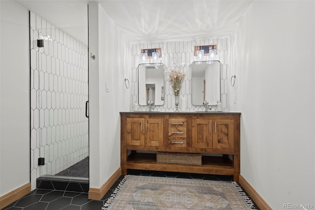 bathroom featuring a stall shower, a sink, tile patterned flooring, double vanity, and baseboards