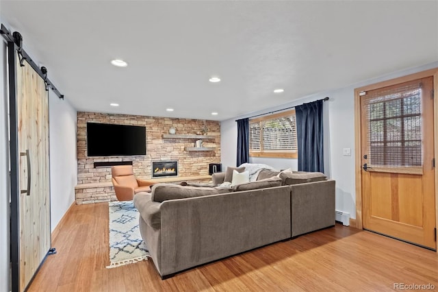 living area featuring recessed lighting, a barn door, a fireplace, light wood finished floors, and a baseboard radiator