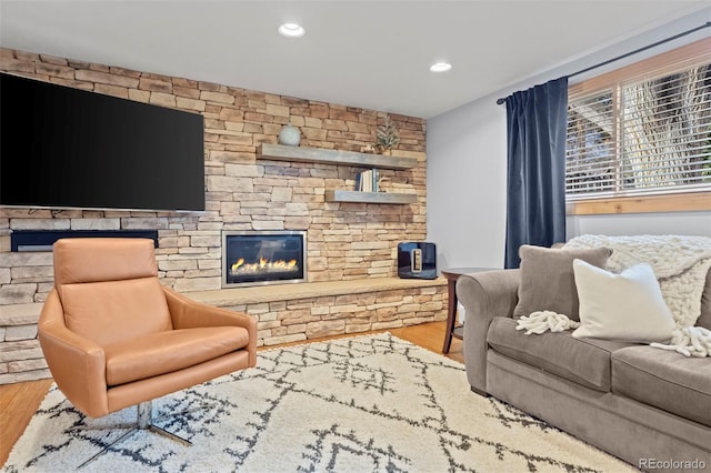 living area with a stone fireplace, recessed lighting, and wood finished floors