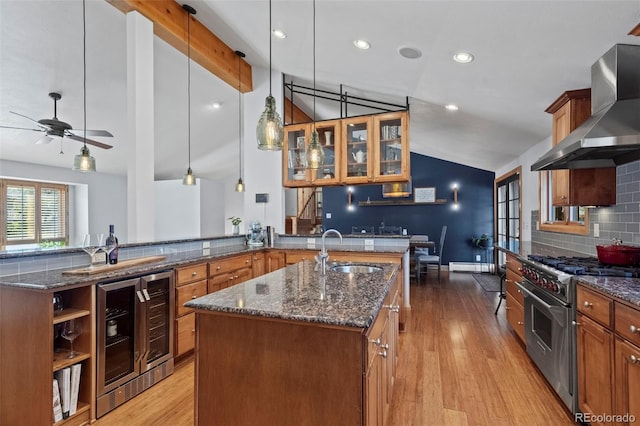 255 Kiowa Pl, Boulder, CO 80303 - kitchen featuring lofted ceiling, wall chimney exhaust hood, a sink, high end range, and a kitchen island with sink