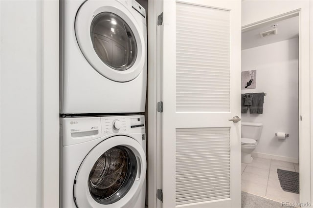 1700 Bassett St Unit 409, Denver, CO 80202 - laundry room featuring stacked washing machine and dryer, tile patterned flooring, and baseboards