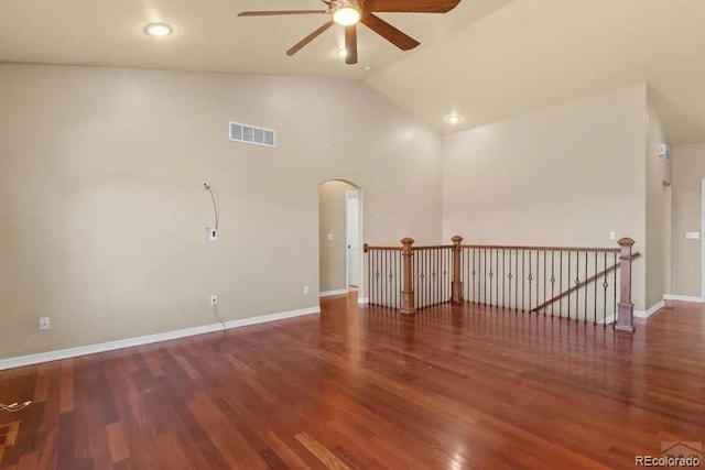 empty room with arched walkways, wood finished floors, visible vents, and lofted ceiling