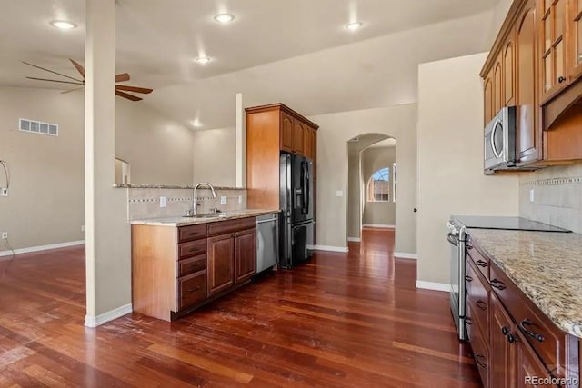 kitchen with light stone countertops, backsplash, stainless steel appliances, vaulted ceiling, and sink