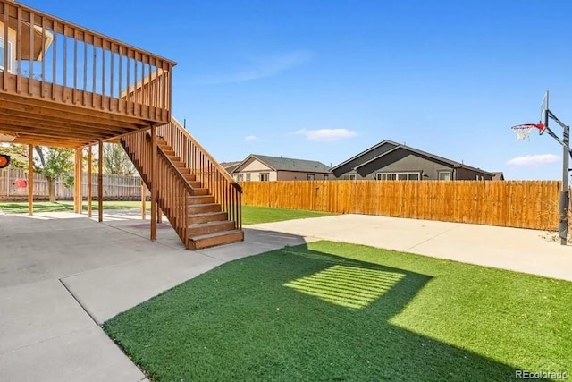 view of yard with basketball court, a deck, and a patio