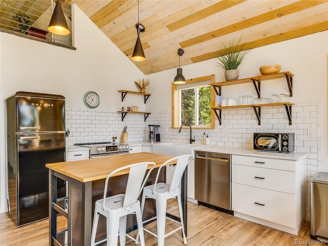 2946 Middle Fork Vis, Fairplay, CO 80440 - kitchen with open shelves, appliances with stainless steel finishes, vaulted ceiling, butcher block counters, and white cabinetry