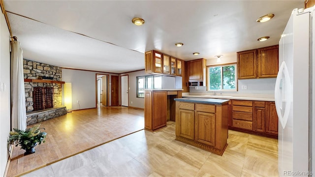 8509 Colorado Ct, Denver, CO 80229 - kitchen with freestanding refrigerator, brown cabinets, a stone fireplace, and a kitchen island