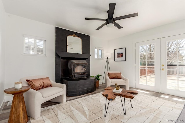 sitting room with french doors, a wood stove, and a ceiling fan