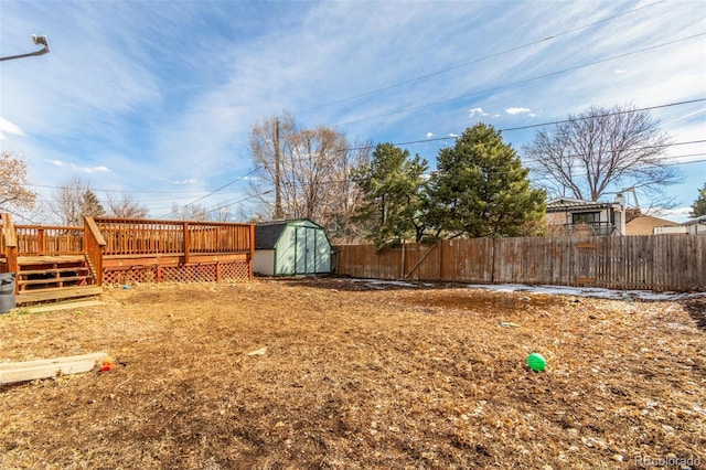 view of yard with a storage shed, a fenced backyard, a deck, and an outbuilding