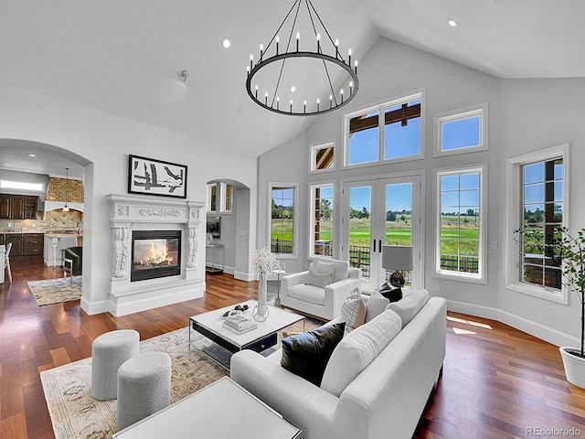 2131 Driver Ln, Erie, CO 80516 - living area featuring arched walkways, high vaulted ceiling, dark wood-style flooring, a chandelier, and a glass covered fireplace