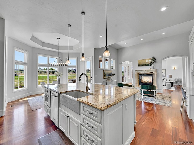 2131 Driver Ln, Erie, CO 80516 - kitchen featuring arched walkways, stainless steel dishwasher, white cabinets, dark wood-style flooring, and recessed lighting