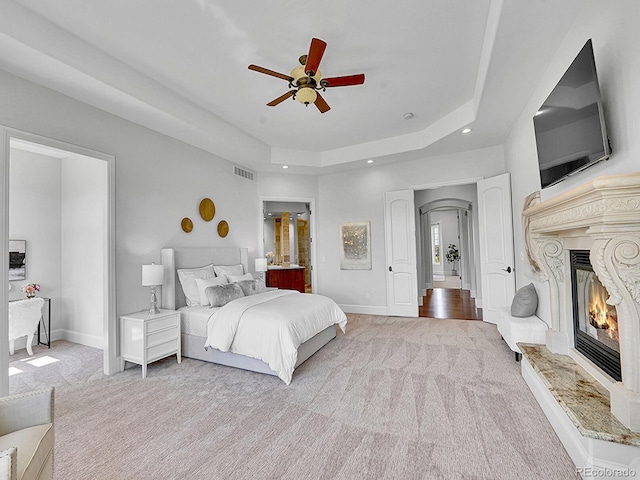 2131 Driver Ln, Erie, CO 80516 - bedroom featuring light colored carpet, recessed lighting, a premium fireplace, a raised ceiling, and a ceiling fan