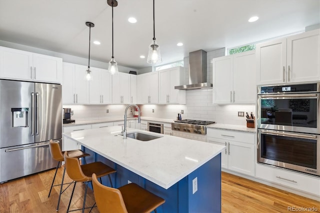 4220 Quitman St, Denver, CO 80212 - kitchen featuring appliances with stainless steel finishes, wall chimney range hood, a kitchen breakfast bar, decorative backsplash, and recessed lighting