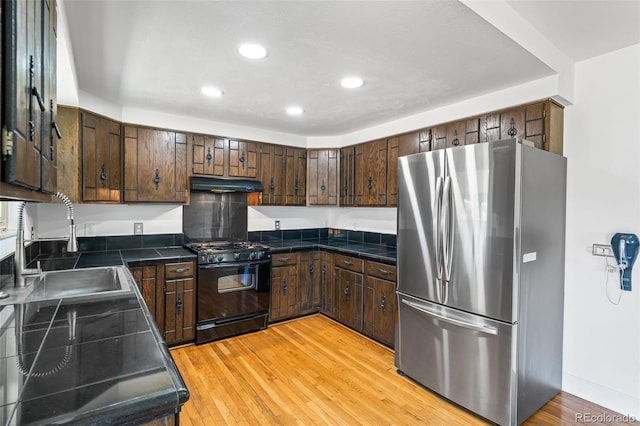 12829 E Nevada Ave, Aurora, CO 80012 - kitchen with freestanding refrigerator, black range with gas stovetop, under cabinet range hood, recessed lighting, and light wood-type flooring