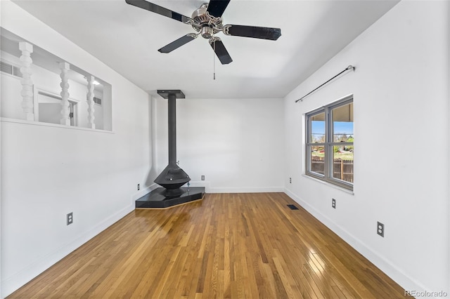 12829 E Nevada Ave, Aurora, CO 80012 - unfurnished living room featuring a wood stove, hardwood / wood-style flooring, a ceiling fan, and baseboards