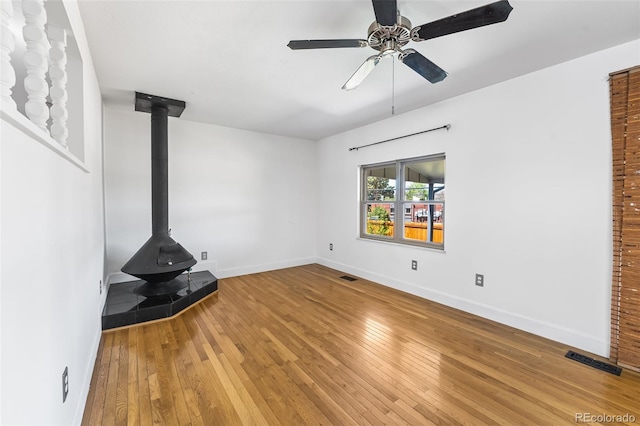 12829 E Nevada Ave, Aurora, CO 80012 - unfurnished living room with a wood stove, hardwood / wood-style flooring, baseboards, and ceiling fan