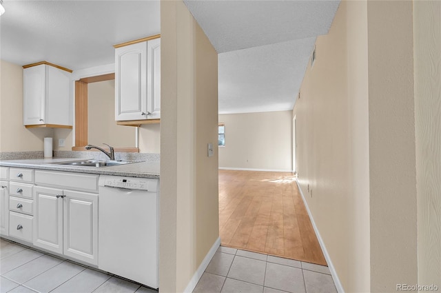 kitchen with light tile patterned floors, white dishwasher, light countertops, white cabinetry, and a sink