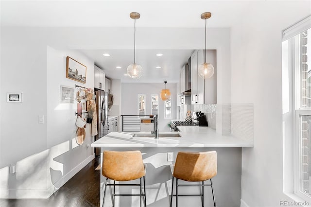 kitchen featuring sink, stove, dark hardwood / wood-style flooring, kitchen peninsula, and hanging light fixtures