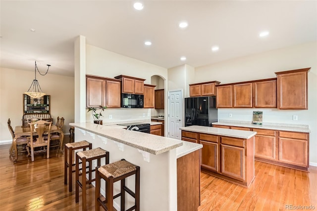 16550 Antero Cir, Broomfield, CO 80023 - kitchen featuring black appliances, brown cabinetry, light wood-style floors, a kitchen bar, and recessed lighting