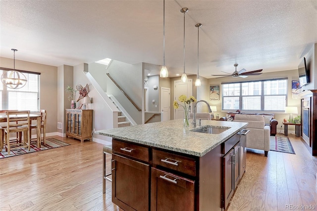 13713 Raritan Ln, Broomfield, CO 80023 - kitchen featuring light wood-style flooring, a ceiling fan, a textured ceiling, pendant lighting, and open floor plan