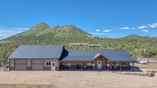 1625 Black Cloud Cir, Westcliffe, CO 81252 - view of front of house featuring a mountain view, a metal roof, a porch, driveway, and a garage