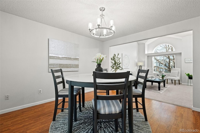 dining area featuring hardwood / wood-style flooring, lofted ceiling, a textured ceiling, and an inviting chandelier