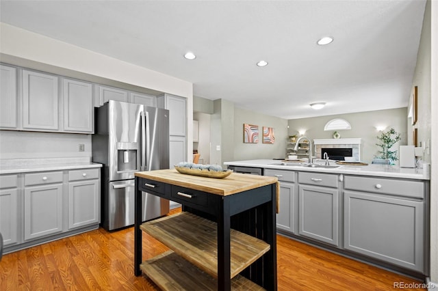 kitchen with gray cabinetry, sink, light hardwood / wood-style flooring, kitchen peninsula, and appliances with stainless steel finishes