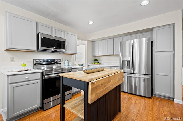 kitchen with appliances with stainless steel finishes, light wood-type flooring, and gray cabinets