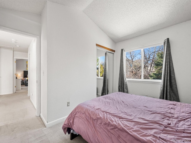 bedroom with a textured ceiling, light carpet, and lofted ceiling