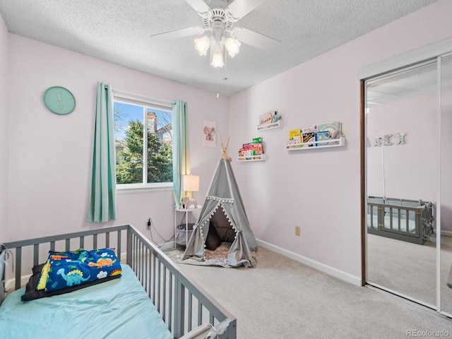 carpeted bedroom with ceiling fan, a textured ceiling, and a closet