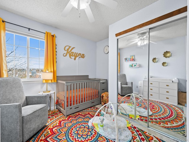 bedroom featuring a textured ceiling, a nursery area, and ceiling fan