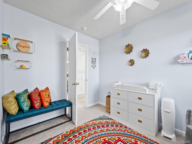 bedroom featuring ceiling fan, light colored carpet, and a textured ceiling