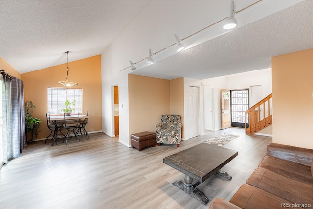 9563 Milwaukee Ct, Thornton, CO 80229 - living room with vaulted ceiling, light wood finished floors, a textured ceiling, stairs, and track lighting