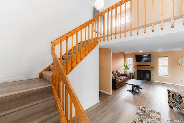 9563 Milwaukee Ct, Thornton, CO 80229 - stairway with wood finished floors, a tiled fireplace, and a towering ceiling