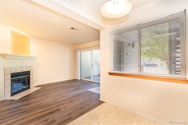 unfurnished living room with a tile fireplace and hardwood / wood-style floors