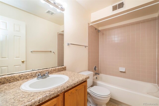 full bathroom featuring vanity, tiled shower / bath combo, and toilet