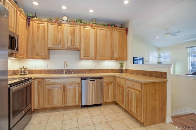 kitchen with stainless steel appliances, light countertops, a sink, and a peninsula