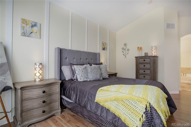 bedroom featuring lofted ceiling, light wood-style floors, and visible vents