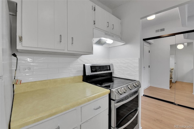 8060 E Girard Ave Unit 514, Denver, CO 80231 - kitchen with under cabinet range hood, range with two ovens, light countertops, tasteful backsplash, and white cabinetry