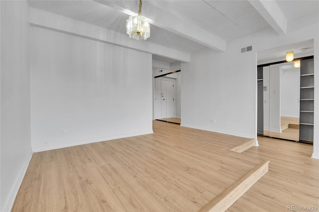 8060 E Girard Ave Unit 514, Denver, CO 80231 - empty room with beamed ceiling, a barn door, light wood-style floors, a chandelier, and a textured ceiling