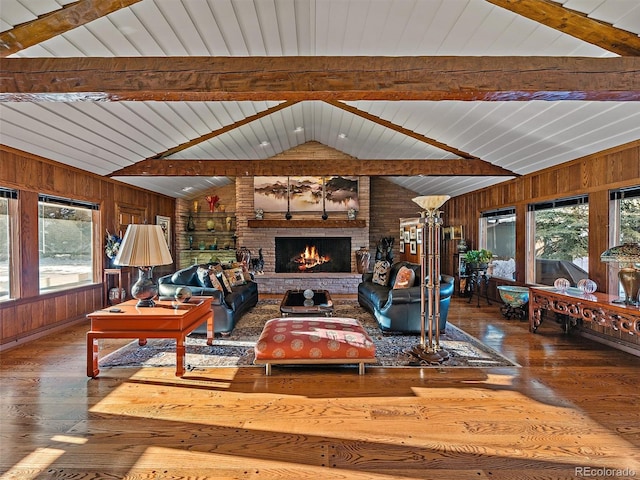 living room with a fireplace, lofted ceiling with beams, brick wall, wooden walls, and hardwood / wood-style flooring