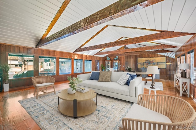 living room featuring vaulted ceiling with beams, wood walls, and hardwood / wood-style flooring