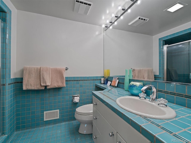 bathroom featuring tile walls, tile floors, large vanity, and toilet