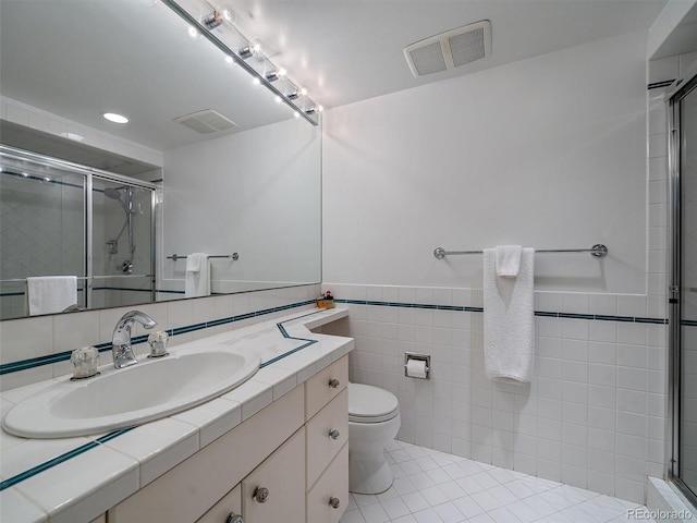 bathroom with tile flooring, an enclosed shower, tile walls, toilet, and vanity