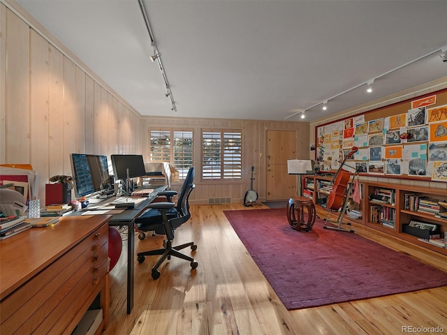 office area featuring light hardwood / wood-style floors, track lighting, and wood walls