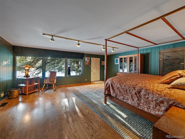 bedroom with wood walls and hardwood / wood-style flooring