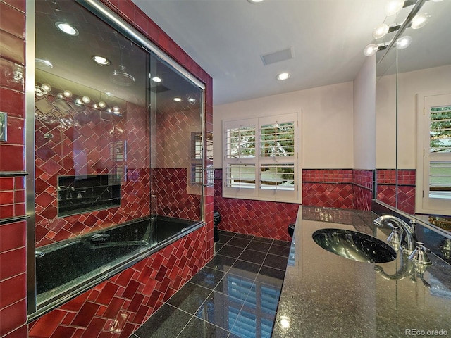 bathroom featuring tile walls, tile floors, a relaxing tiled bath, and large vanity